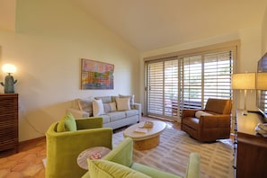 A living room with a sofa, armchairs, a coffee table, and a painting on the wall.
