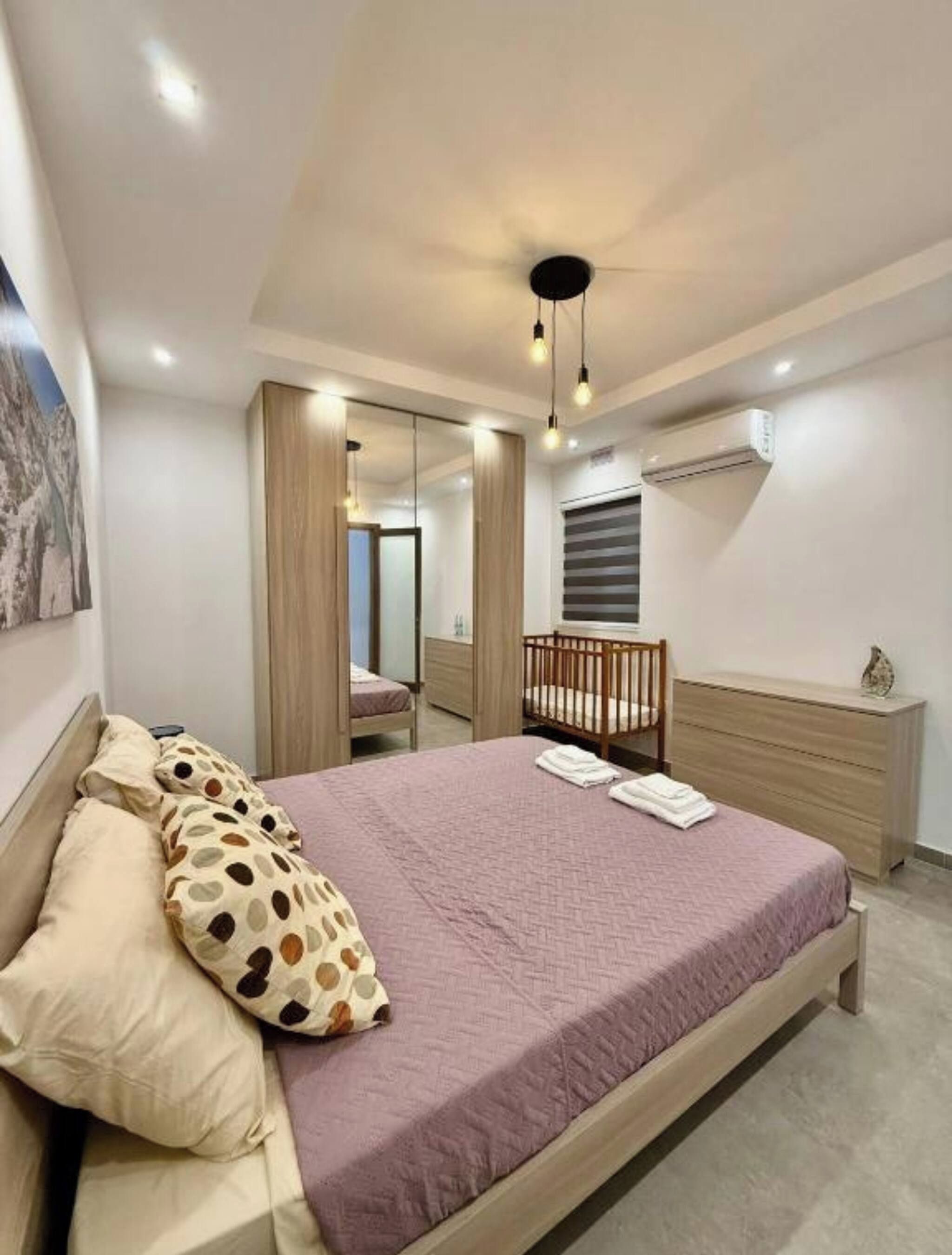 Une chambre à coucher avec un lit, un berceau, une commode et un miroir.