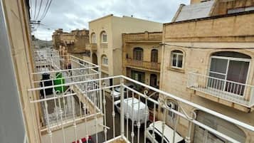 A residential area with a balcony overlooking a street with parked cars and neighboring buildings.
