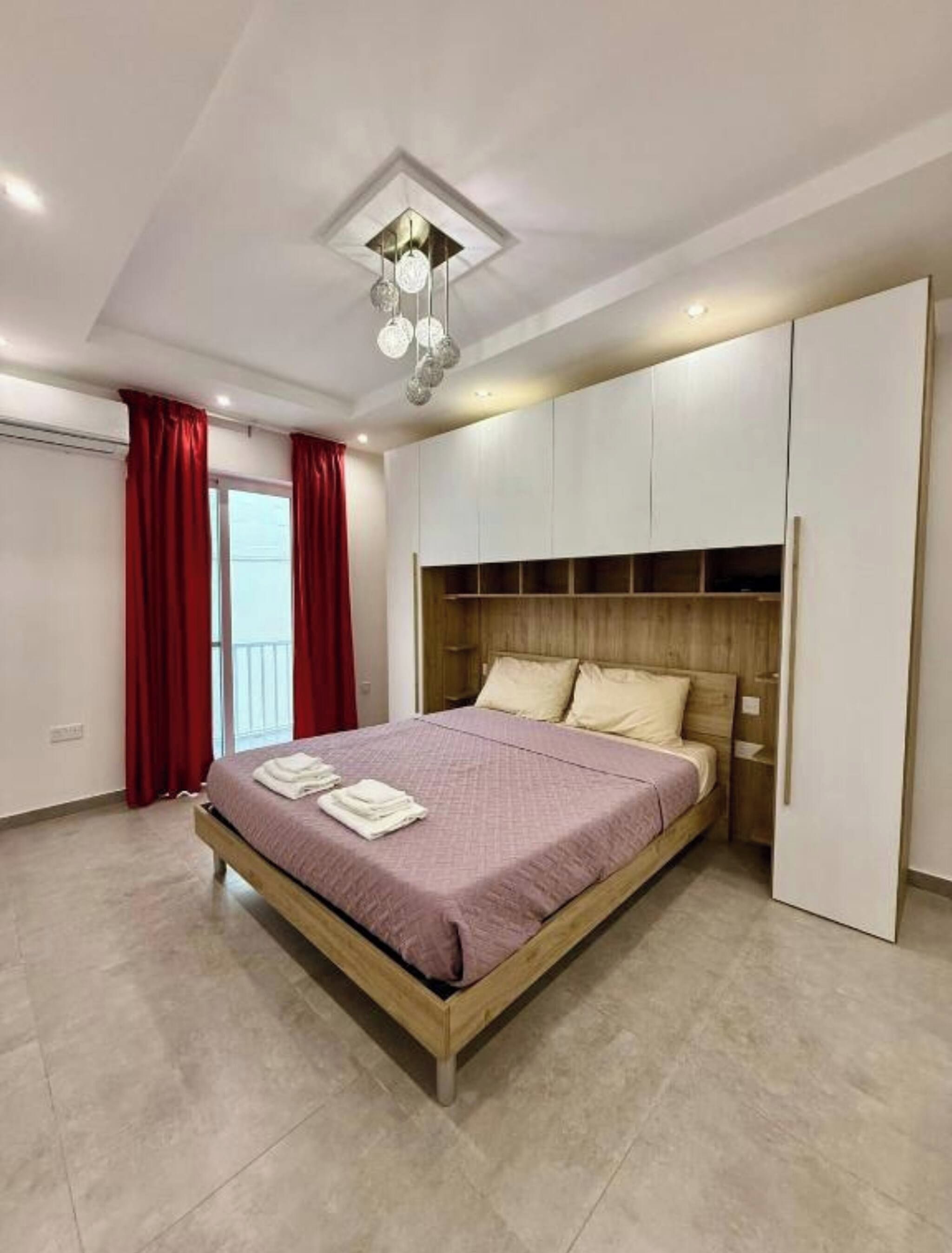 Een moderne slaapkamer met een bed, een inbouw kast en een plafondlamp.