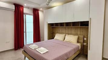 A modern bedroom with a bed, built-in wardrobe, and a ceiling light fixture.