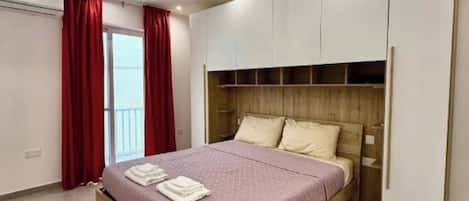 A modern bedroom with a bed, built-in wardrobe, and a ceiling light fixture.