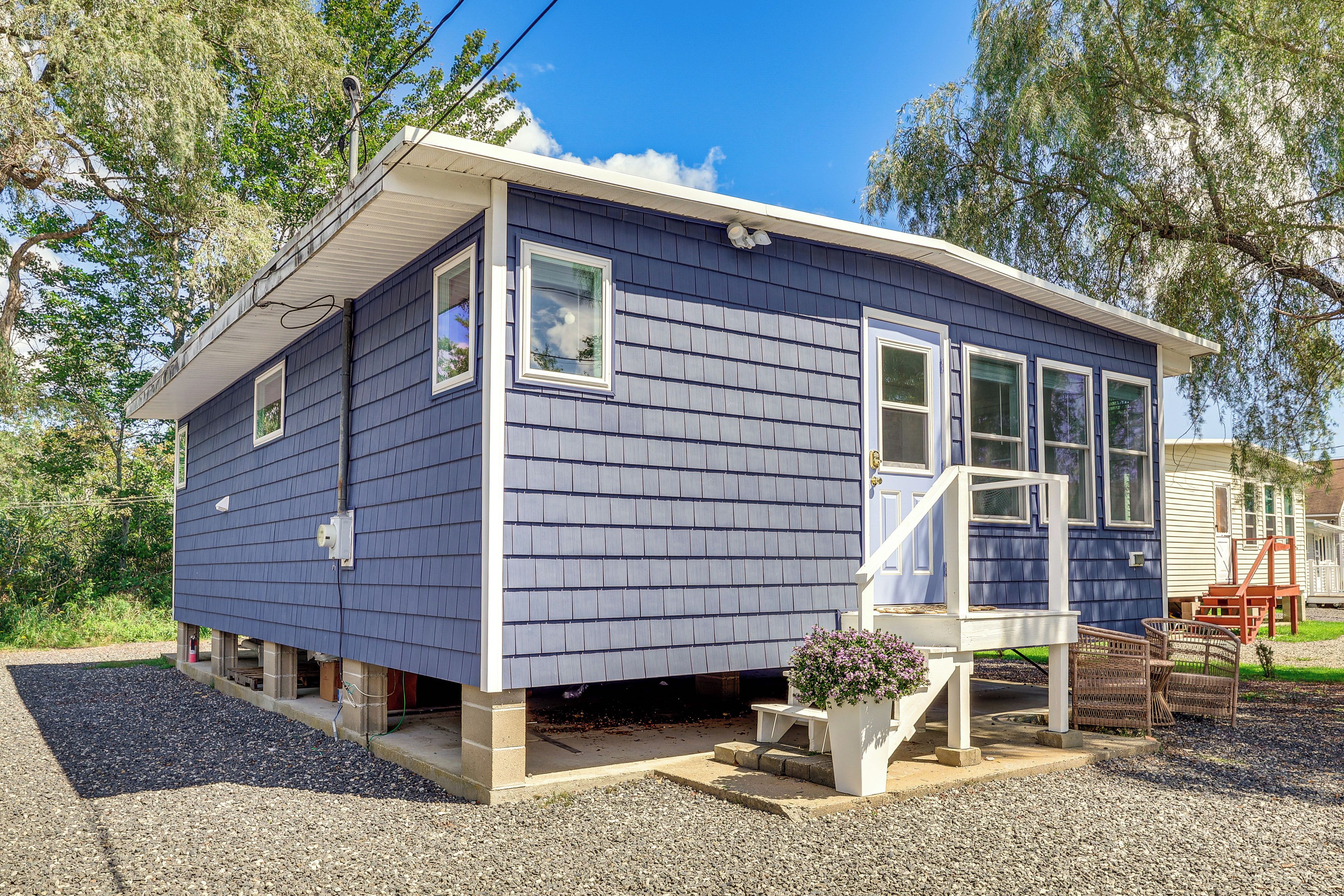 Une petite maison à un étage, à l’extérieur bleu, avec un porche à l’avant et un petit jardin.