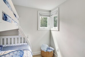 Ein Kinderstockbett mit weißem Gestell und blau gestreifter Bettwäsche.