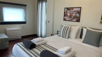 Quarto de hotel com cama, janela com cortinas, ar condicionado e um quadro na parede.