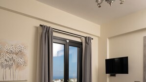 Une chambre à coucher avec un lit, un téléviseur fixé au mur et une vue sur la mer, visible à travers une porte coulissante.
