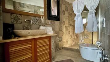 A bathroom with a wooden vanity, a large mirror, a bathtub, and two towels hanging on hooks.