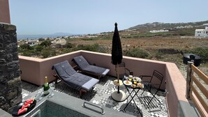 Une terrasse sur le toit, avec des chaises longues, une table où est servi le petit-déjeuner et une vue sur le paysage.