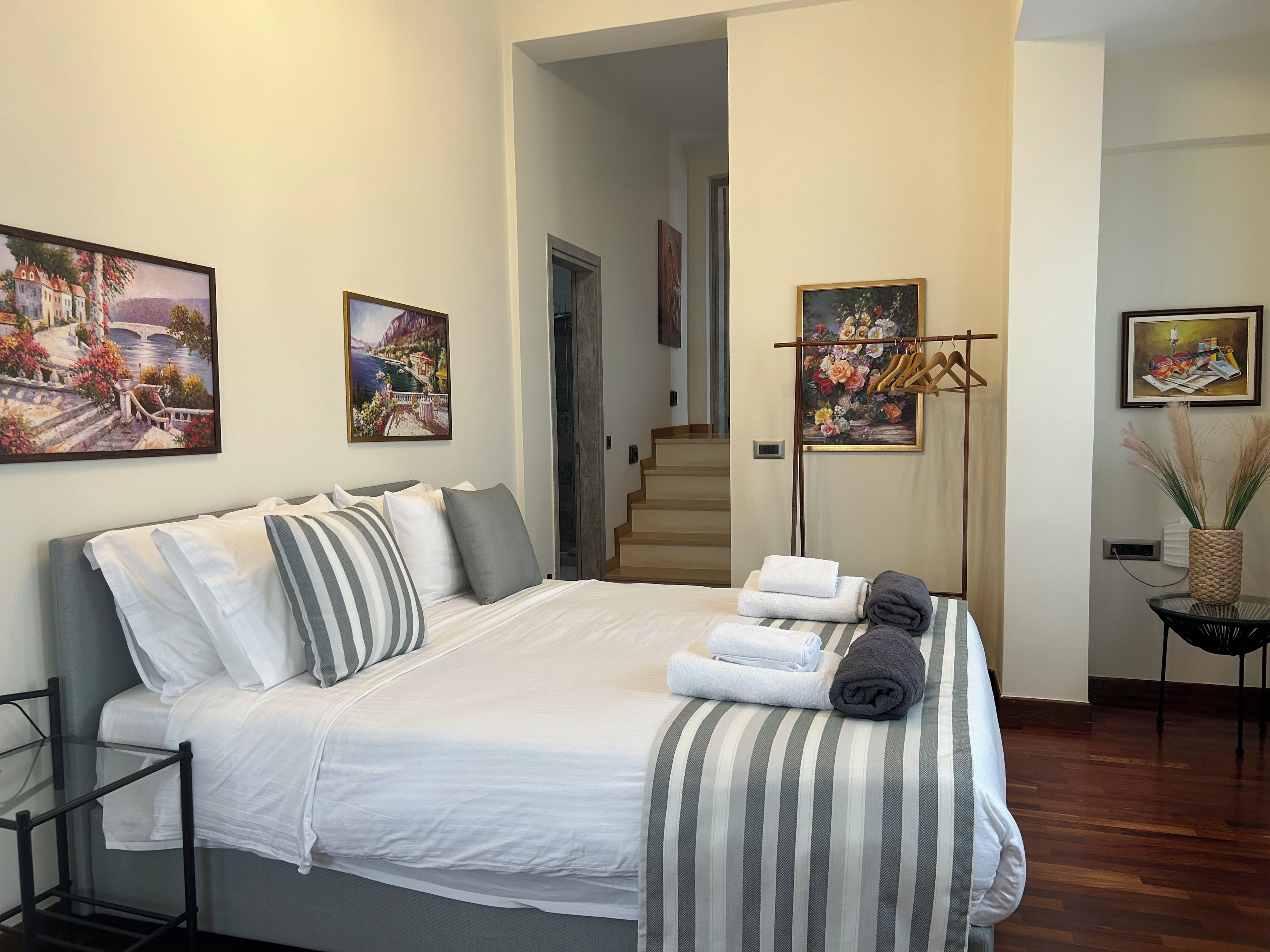 A bedroom with a bed, pillows, a bedside table, and a painting on the wall.