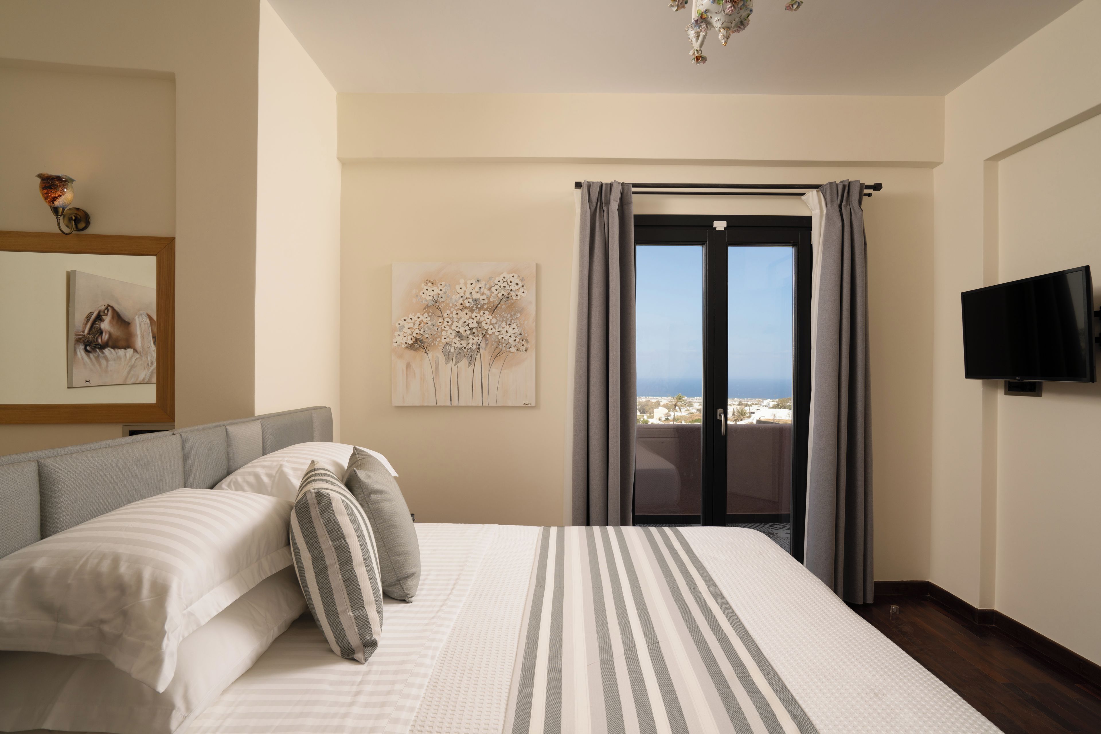 Habitación de hotel con cama, un cuadro, televisión y vista al mar.