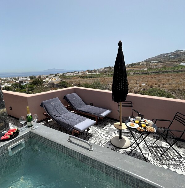Un espace piscine aménagé sur le toit, avec deux chaises longues, une table pour le petit-déjeuner et une vue sur le paysage.