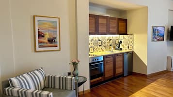 Un salon avec un canapé et un tableau, une cuisine avec des meubles en bois et un dosseret carrelé, et un plancher en bois.