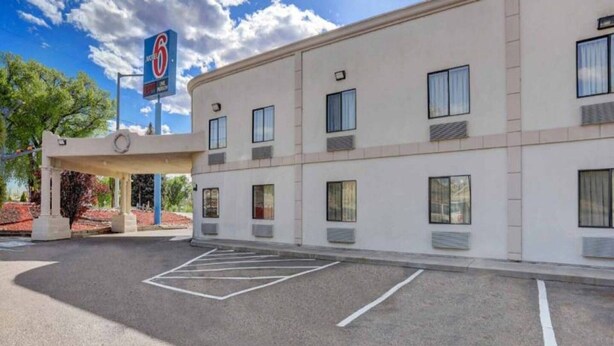 Un hotel con parcheggio, ingresso coperto e insegna che indica una valutazione a 6 stelle.