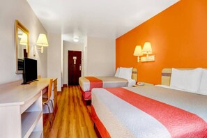 Habitación de hotel con dos camas, un escritorio, una silla, un televisor y una puerta que da a otra habitación.