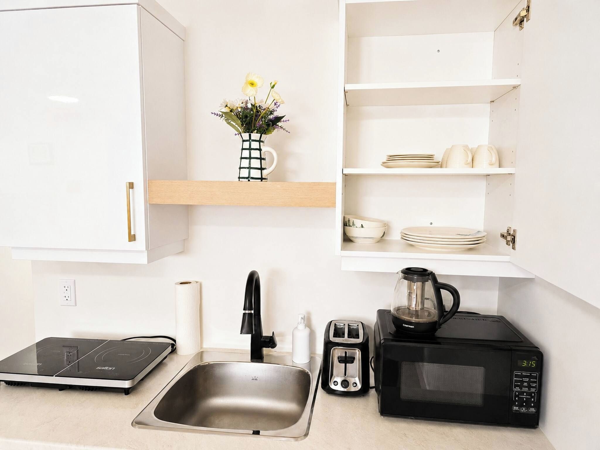 A kitchen with a sink, a toaster, a coffee maker, and a microwave.