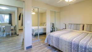 Una camera da letto con un letto, una scrivania e una sedia. È presente anche una ventola a soffitto e uno specchio.