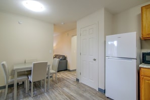 A compact kitchen with a refrigerator, a dining table with chairs, and a wooden cabinet. - See the Royal Gorge! Cañon City Apartment (Cañon City)