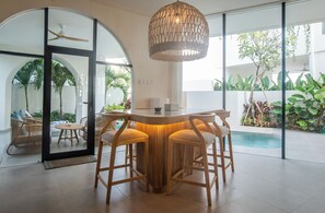 Ein modernes Interieur mit Barbereich, großen Fenstern und Zimmerpflanzen.