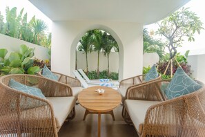 A sunlit outdoor seating area with wicker furniture and a central round table. - Kona Resort Pererenan A (Badung)