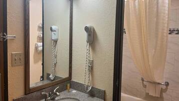 A bathroom with a sink, mirror, hair dryer, and shower curtain.