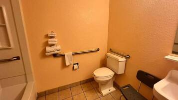 Un baño con inodoro, barra de apoyo y perchero para toallas.