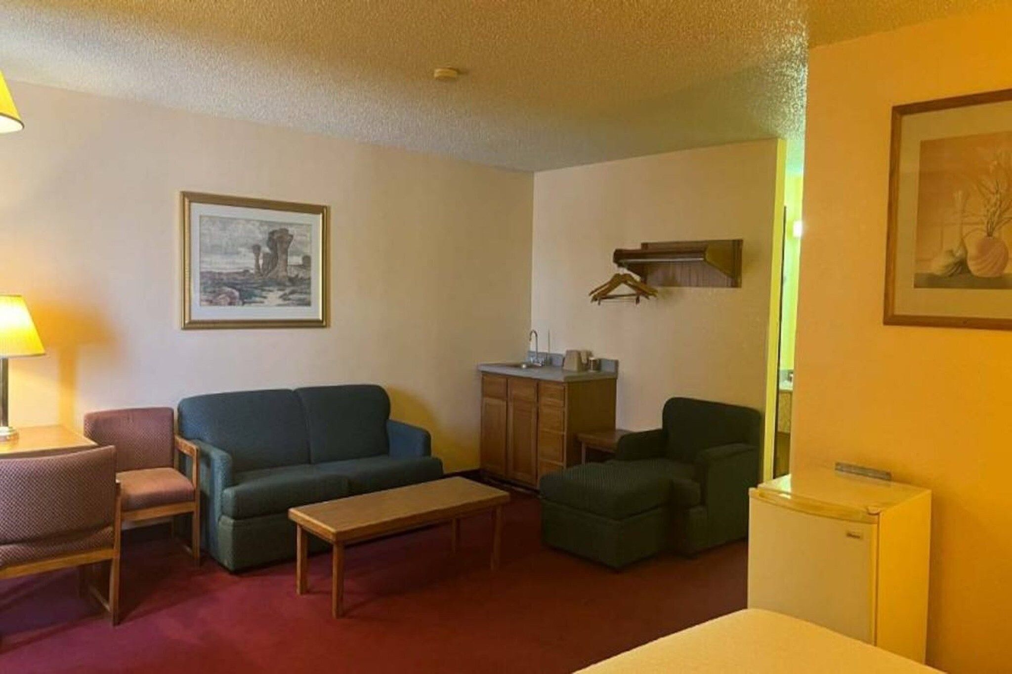 A compact living space with a sofa, a small table, a cabinet, and a refrigerator.