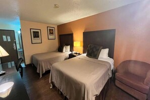 Habitación de hotel con dos camas, un escritorio, una silla y una puerta.