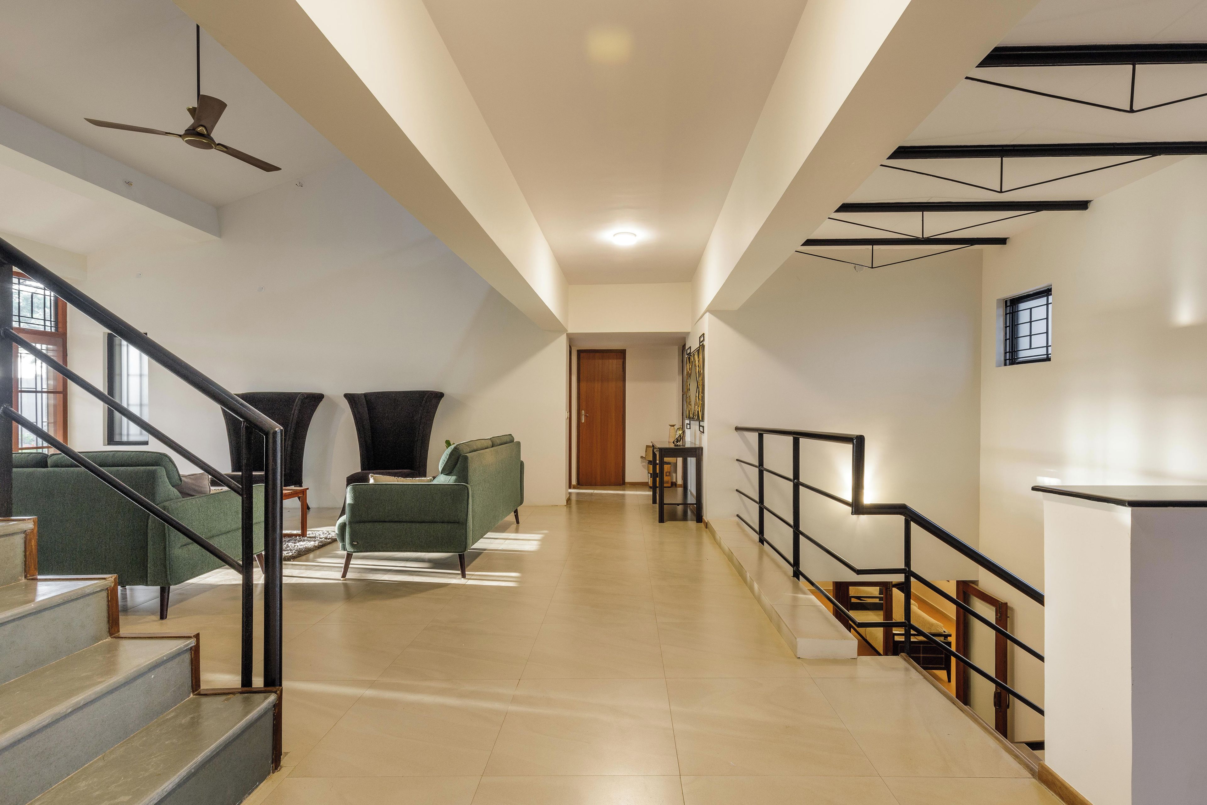 A spacious living area with a staircase, a ceiling fan, and a view into another room.