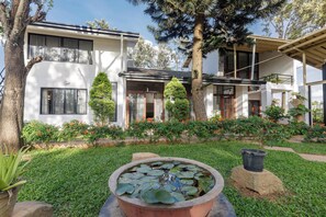 A modern two-story house with a well-maintained garden, including a pond with lily pads. - Grandeur 5bhk Villatheatre Hennurmanyata (Bengaluru)