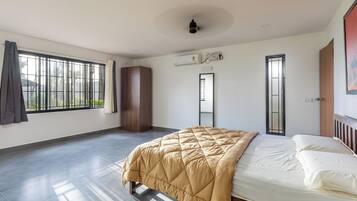 A bedroom with a bed, a wardrobe, a window with a view, and an air conditioning unit.