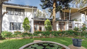 Una moderna casa a due piani con un giardino curato, che include uno stagno con ninfee e piante fiorite.