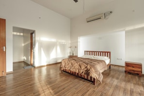 Quarto com cama de madeira, mesa de cabeceira pequena e ar-condicionado fixado na parede.