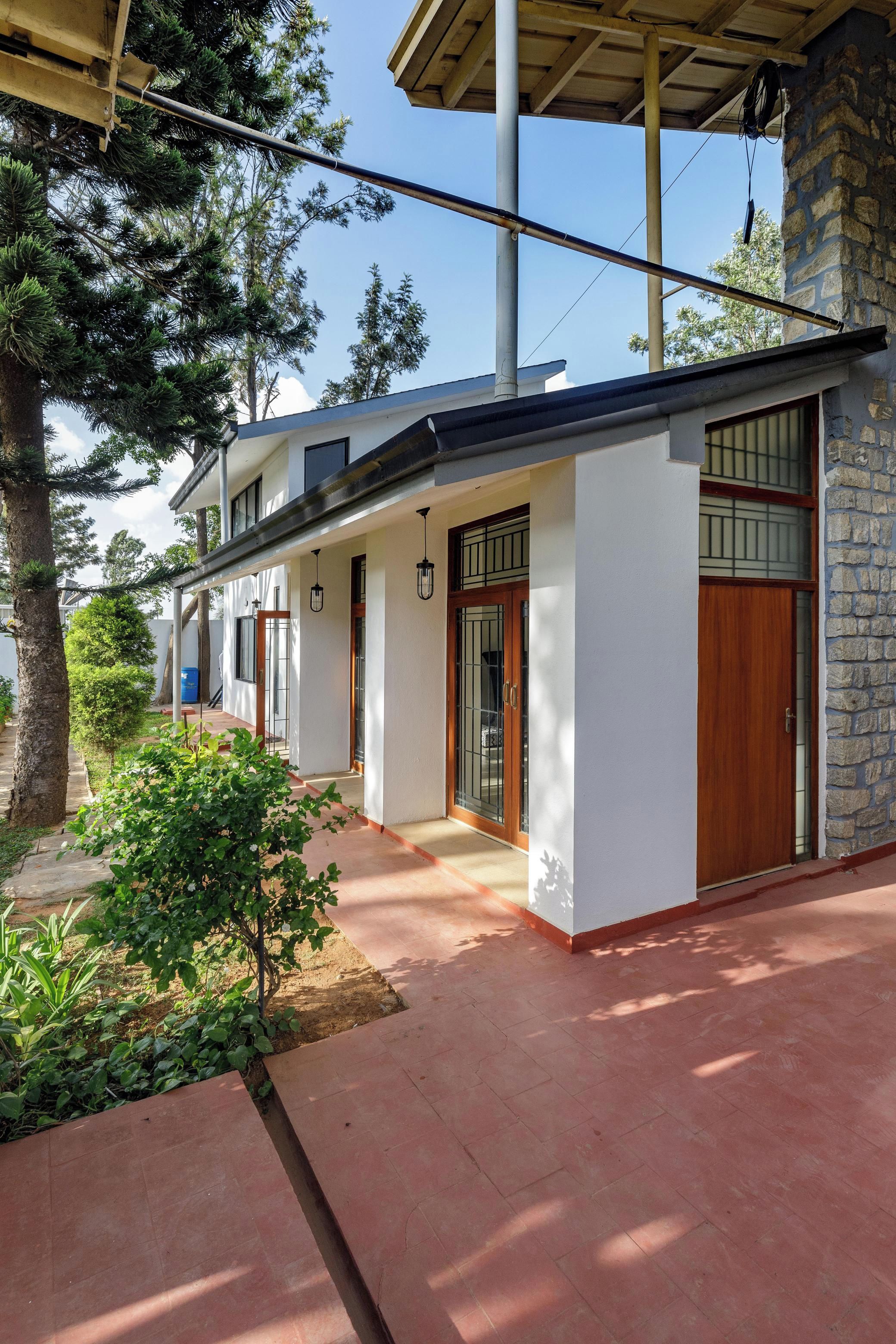 A modern house with a covered porch, a stone wall, and a small garden area.