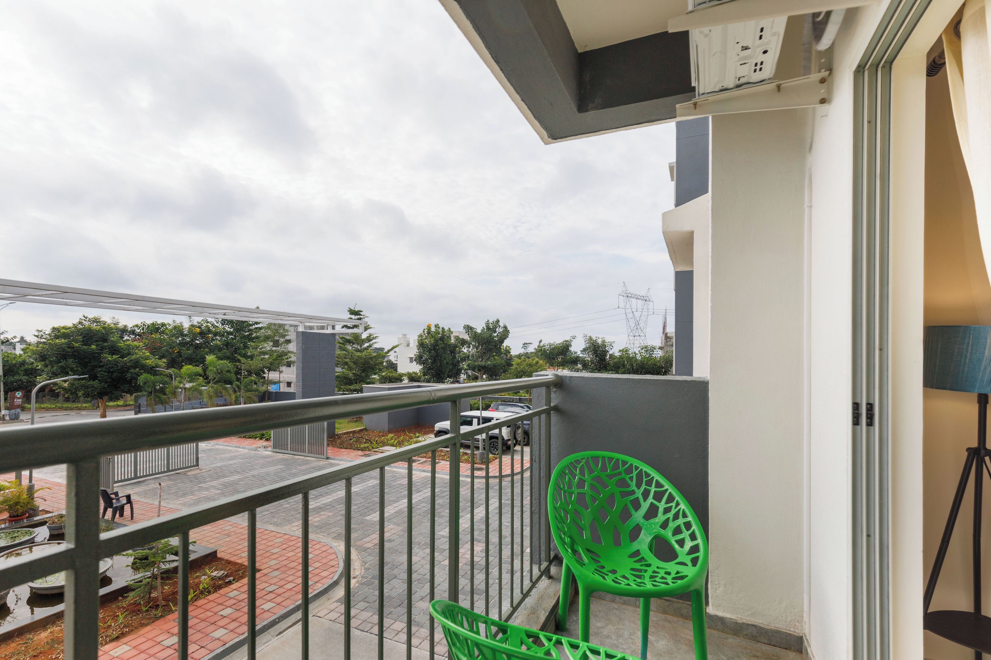 Ein Balkon mit einem grünen Stuhl, einem Metallgeländer und Blick auf die Straße und die Gebäude.
