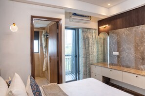 A modern bedroom with a large bed, a bathroom with a shower, and a balcony with a view. - Belmont by Redolive 3bhk 30min DLF Cyber City (Sohna)