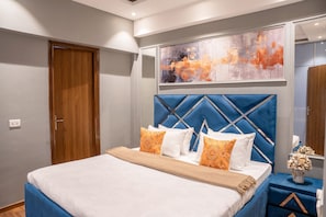 A modern bedroom with a large bed, a headboard with a geometric pattern, and a painting above the bed. - Belmont by Redolive 3bhk 30min DLF Cyber City (Sohna)