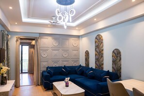 A modern living room with a blue sectional sofa, a marble coffee table, and decorative wall panels. - Belmont by Redolive 3bhk 30min DLF Cyber City (Sohna)