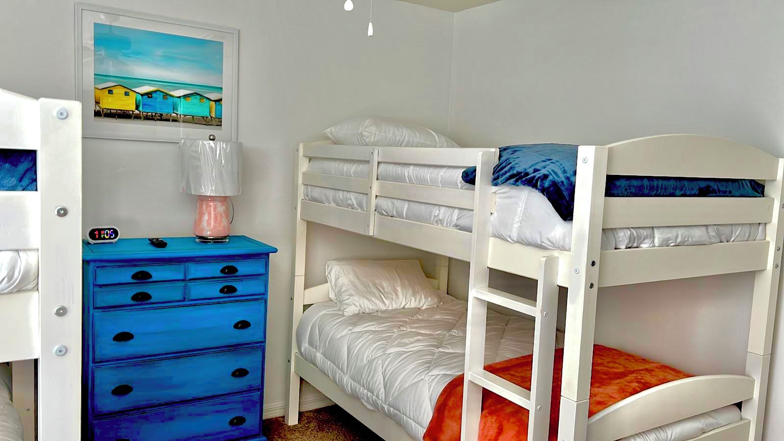 A bunk bed room with a dresser and a clock.