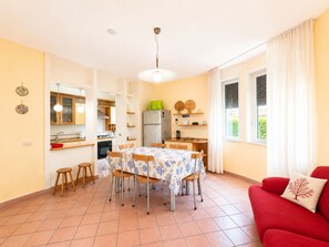 Ein gemütlicher Wohnbereich mit Essplatz, Küche und einem roten Sofa.