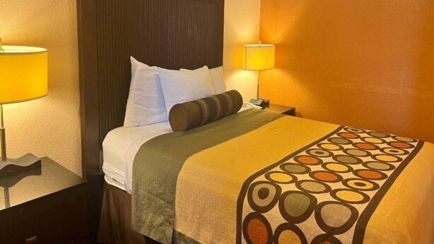 A hotel room with a bed, two bedside lamps, a headboard, and a patterned bedspread. - 1 King Bed | Non-Smoking, Micfridge (Deming NM)