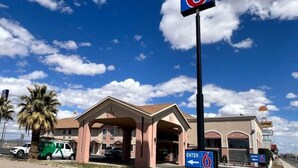 A motel with a large '6' sign, a covered entrance, and a parking area with a green van. - 1 King Bed | Non-Smoking, Micfridge (Deming NM)