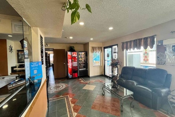 A reception area with a counter, a vending machine, a sofa, and a decorative plant.