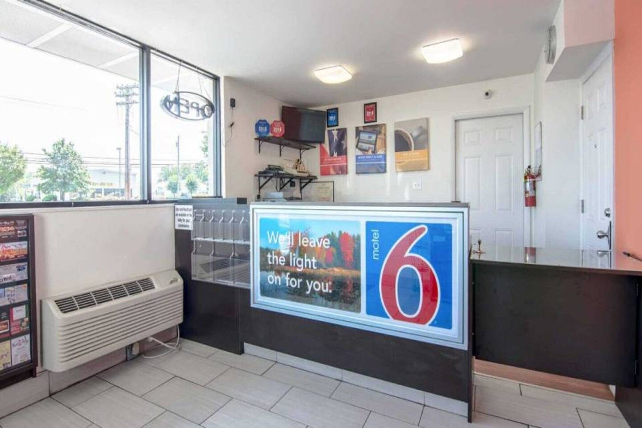 Ein Motelinneres mit einer Rezeption, einem Fenster mit Ausblick und einem an der Wand befestigten Feuerlöscher.