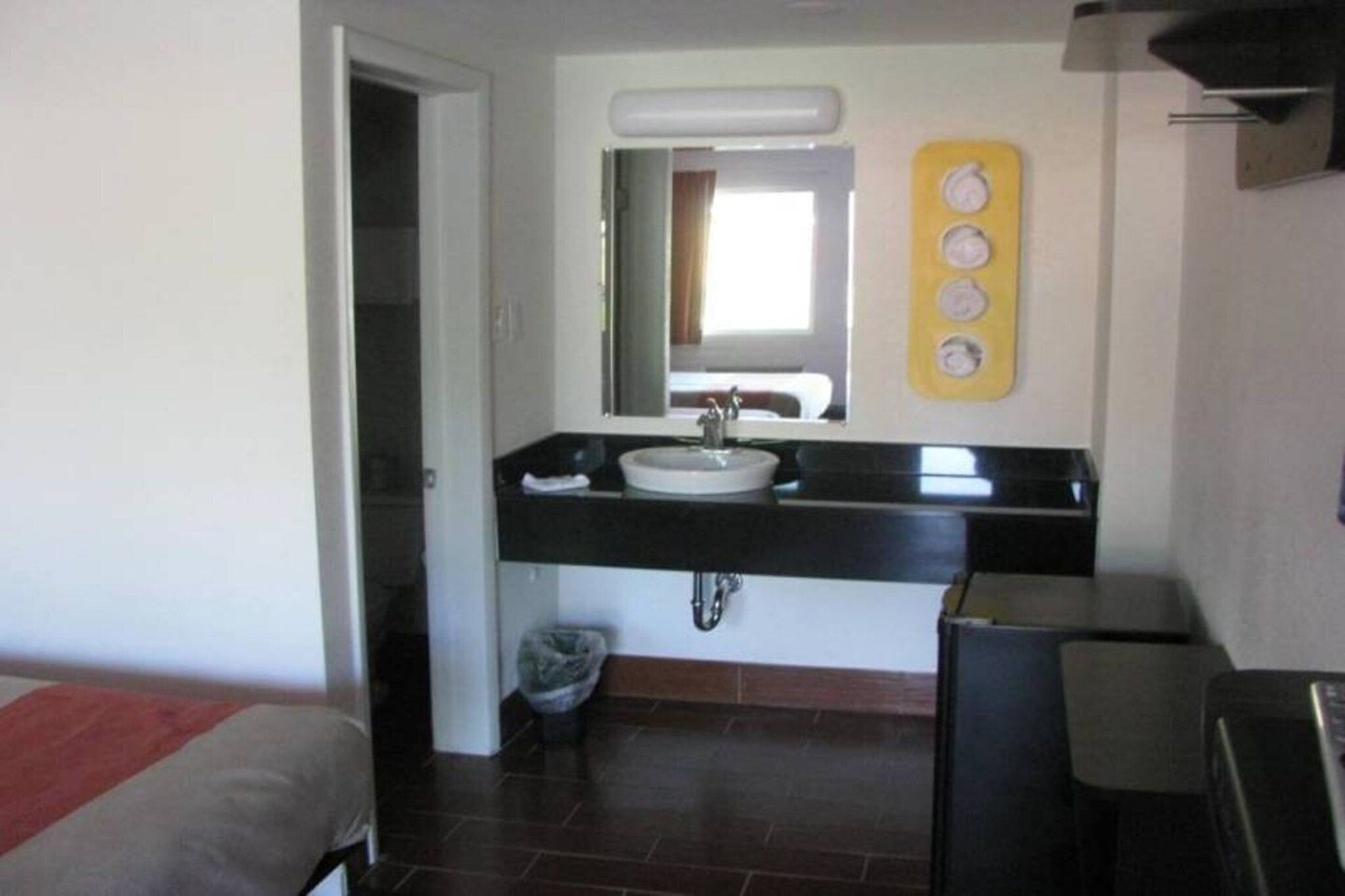 Ein Hotelzimmer mit einem Badezimmer, das ein Waschbecken, einen Spiegel und eine Mülltonne enthält.