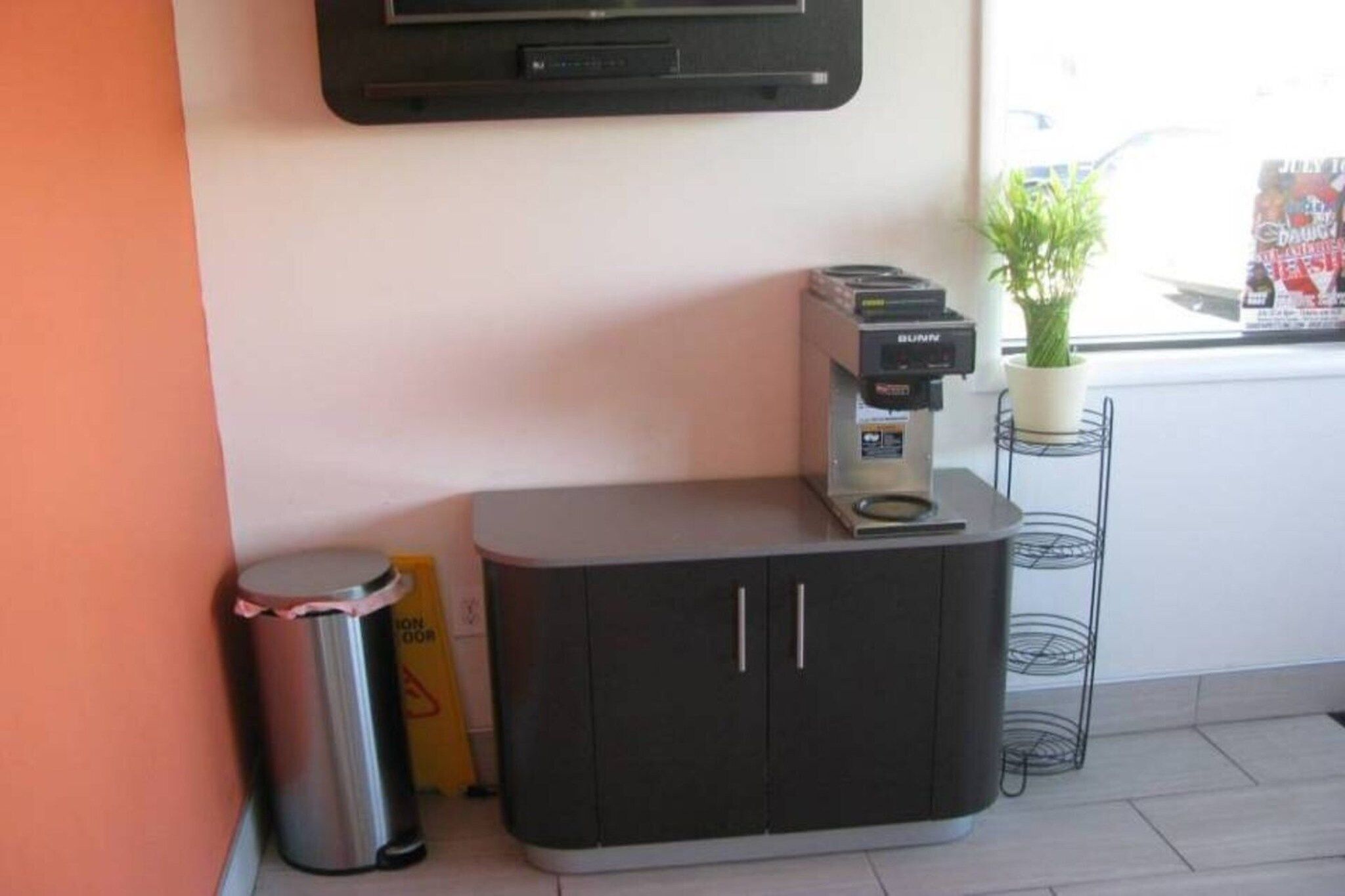 Eine Küchenzeile mit einer Kaffeemaschine, einem Mülleimer und einer Topfpflanze.