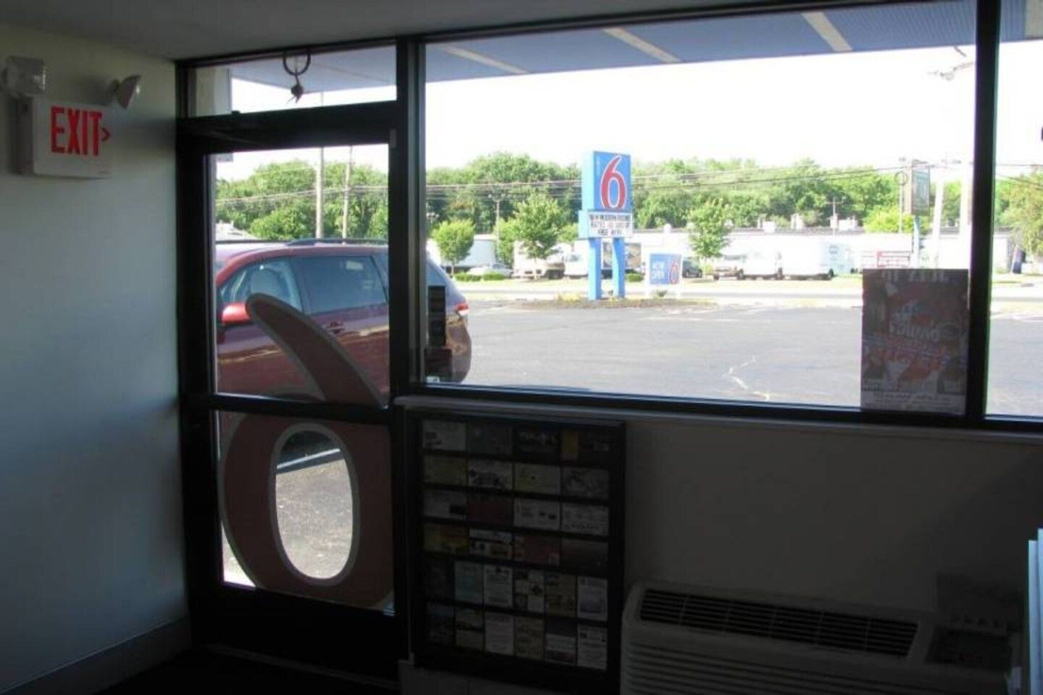 A window with a view of a parking lot and a blue sign with the number 6.