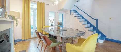 A dining area with a round table, chairs, and a staircase.