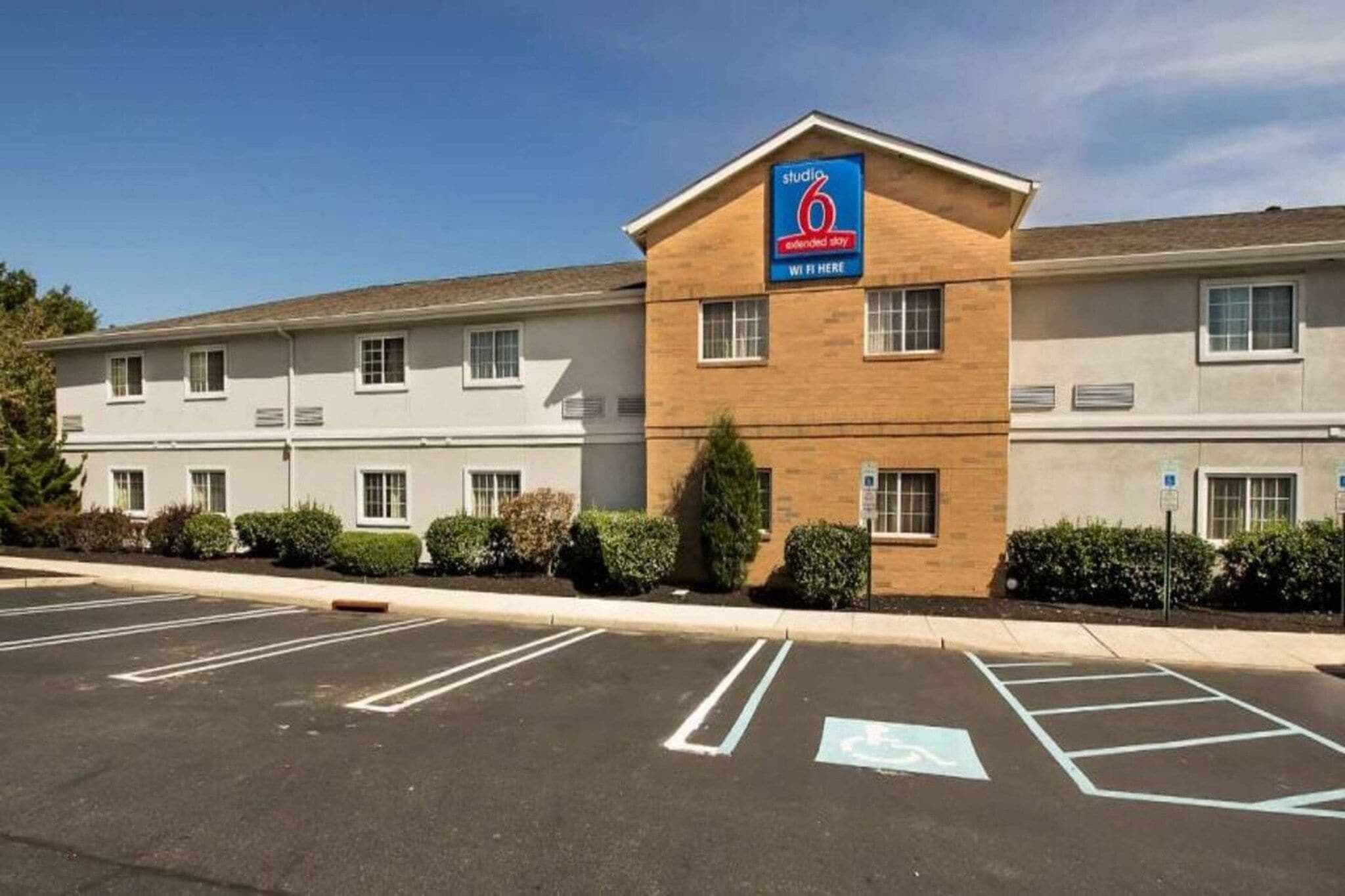 A hotel with a sign indicating it is a 6-star establishment. There are multiple parking spaces, including a handicapped parking space.