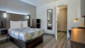 A modern hotel room with a bed, bedside tables, a mirror, and a desk with a lamp. - 1 Full Bed | ADA | Tub (Richland)