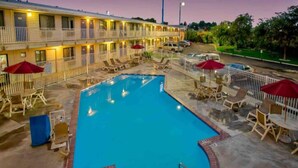 A hotel with a swimming pool, outdoor seating, and a fenced area. - 1 Full Bed | ADA | Tub (Richland)